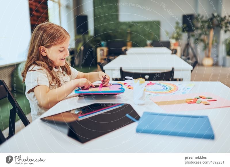 Schoolgirl doing homework sitting at desk in afterschool club. Girl drawing pictures. Learning at primary school. Elementary education. Back to school child