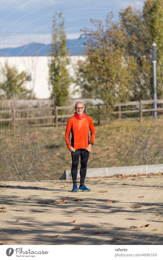 Front view of senior man in sport clothes standing in a city park front view jogging running sunny day happy exercise fitness pensioner lifestyle health