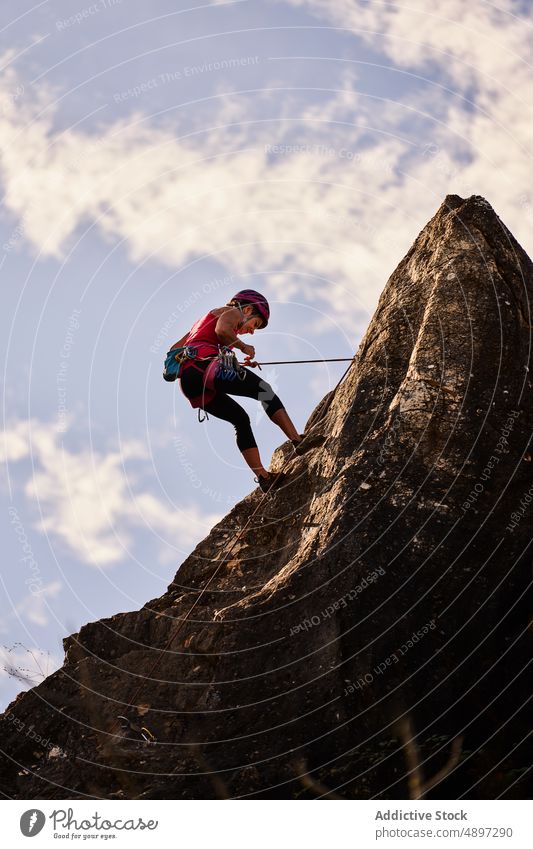 Senior Woman Climbing On Rocky Cliff Against Sky Active Low Angle Climber Hiker Harness Adventure Danger Retirement Hiking Fitness Athlete Activity Vacation