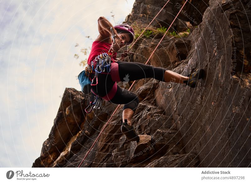 Senior Woman Climbing On Rocky Cliff Against Sky Active Low Angle Climber Hiker Harness Adventure Danger Retirement Hiking Fitness Athlete Activity Vacation