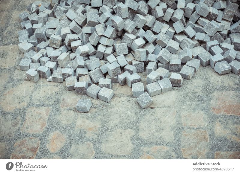 Heap of stone blocks on pavement brick pile construction site dirty grunge many path build industry shabby rough way rock structure weathered street heap