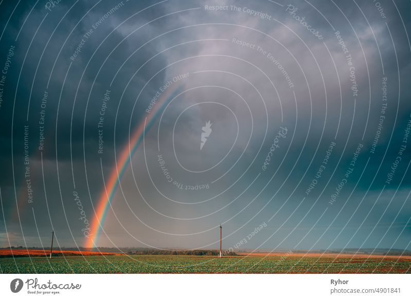 Dramatic Sky During Rain With Rainbow On Horizon Above Rural Landscape Field. Agricultural And Weather Forecast Concept. Countryside Meadow In Autumn Rainy Day