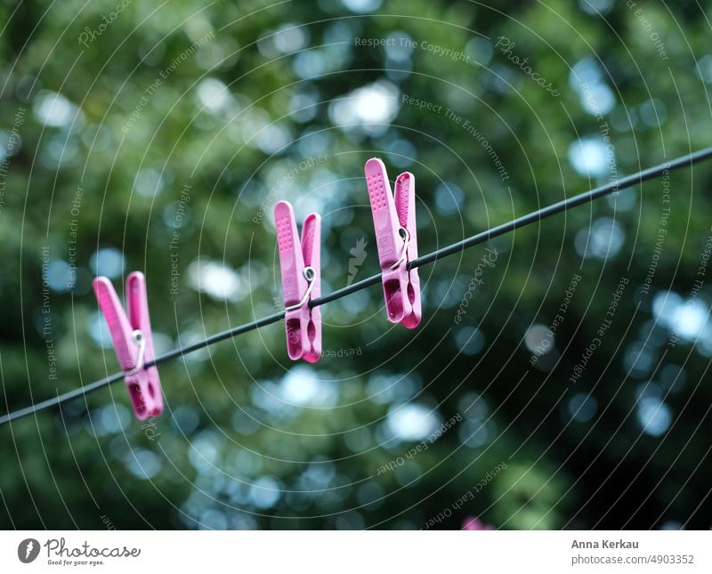 Three pink clothespins on the clothesline against green background Clothes peg Pink three Droop Holder Laundry Hang spanned Washing Washing day