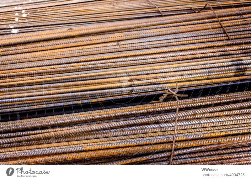 Rusting metal rods tied together in sunlight, diagonal Metal Bound Construction site rust colored Iron twisted background quantity structure reinforcing bars