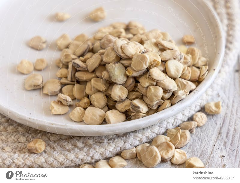 Plate of raw dry Grass pea close up on wooden table. Legumes known in Italy as Cicerchia cicerchia grass pea white diet dried food copy space healthy ingredient