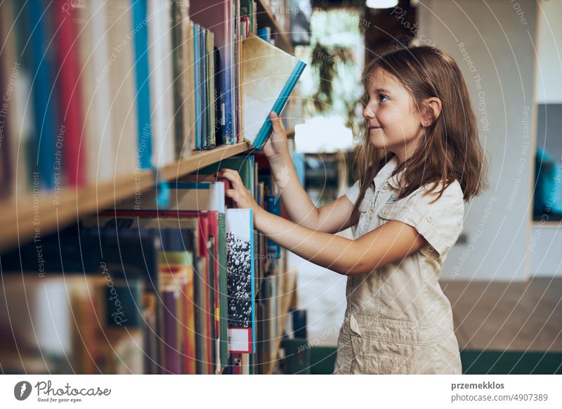 Schoolgirl choosing book in school library. Smart girl selecting literature for reading. Learning from books. Benefits of everyday reading. Child curiosity. Back to school