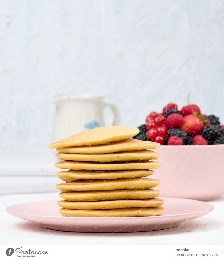 Stack of baked pancakes with fruits in a round plate on a white table black sugar stack breakfast food sweet meal homemade dessert delicious fresh tasty snack