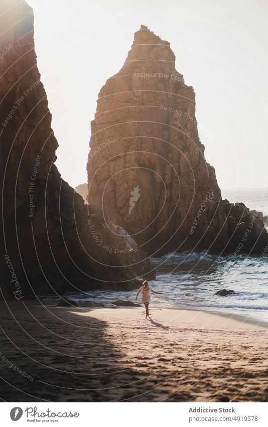 Woman running on shore with cliffs woman traveler sea rock beach water sunset journey sunlight sundown tourist evening pastime leisure adventure active female