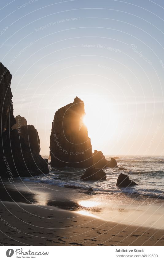 Rocky cliffs near waving sea rock beach water shore nature coast coastal wave tropical wild splash tide foam shadow summer sunlight sand resort seashore ocean