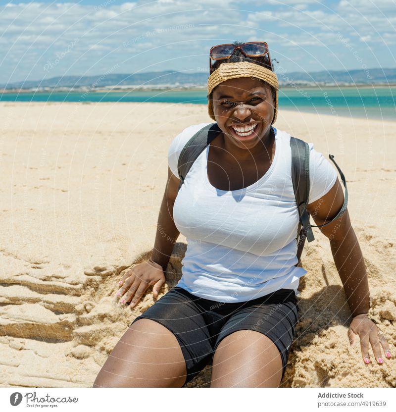 Black woman smiling sitting on the sand at the beach black sea seashore summer girl smile happy looking at camera beautiful young female lifestyle travel ocean