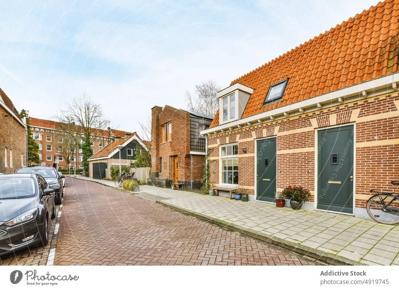 Street with houses lined up next to parked cars street sidewalk architecture city pavement town day urban outdoors road cityscape community no people window