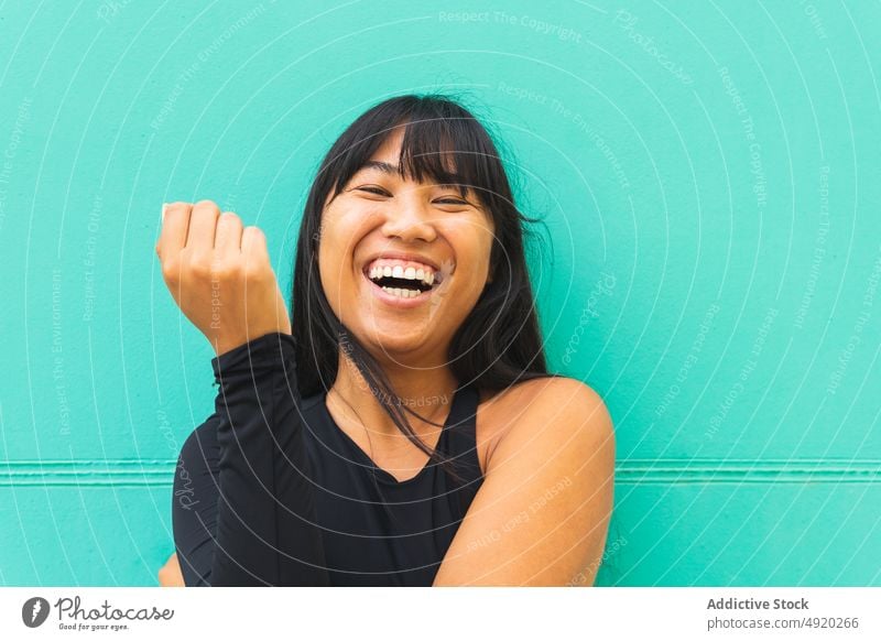 Happy Asian woman against turquoise wall smile happy urban street style appearance portrait sincere female young ethnic asian long hair cheerful glad daytime