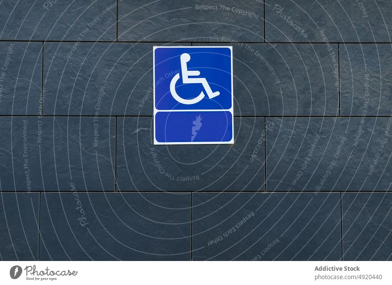 Accessibility sign on gray wall access blank disable icon building street handicap wheelchair modern empty geometry signage symbol public message structure