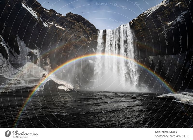 Waterfall on sunny day waterfall rainbow frozen snow mountain vacation landscape winter amazing flow ice stream tourism iceland explore explorer travel nature