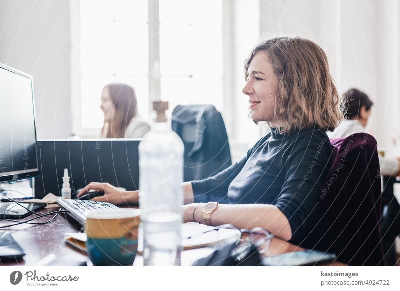 Women in startup business and entrepreneurship. Yound devoted female AI programmers and IT software developers team programming on desktop computer in startup company share office space.