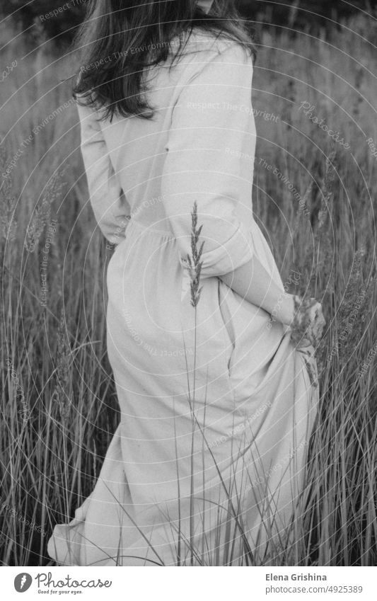 A young woman in a linen dress walks through a grassy field. girl hair flowers summer closed eyes portrait calmness lifestyle slowdown brunette beautiful