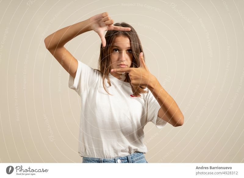 Teenage latin girl wearing casual white t-shirt smiling making frame with hands and fingers with happy face. creativity and photography concept isolated people
