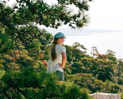 Girl walking under a pine tree, looking at the sea Hiking Cap Jawbone baseball cap Green Nature Ocean vacation Summer Tree Forest Relaxation