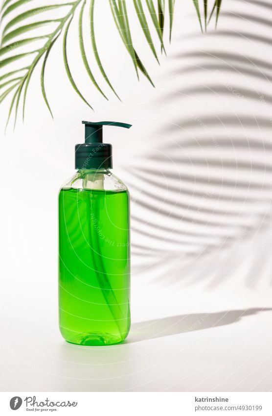 Cosmetic pump dispenser bottle filled with green liquid on white, Palm leaf hard shadows pink cosmetics mockup negative space copy space close up Brand