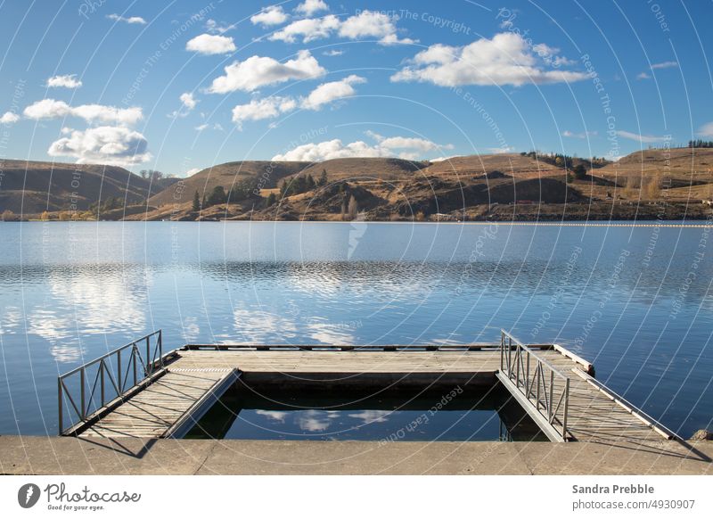 A geometric landscape image of a jetty, lake and distant hills Lake Dunstan Sandra Prebble Clyde dam mid day holiday no one there empty calm hydro dam boating