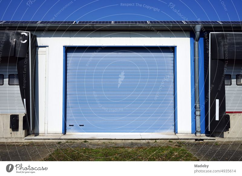 Blue roller shutter and industrial door of a large warehouse in front of blue sky in the sunshine in Ibbenbüren in the district of Steinfurt in Westphalia, Germany