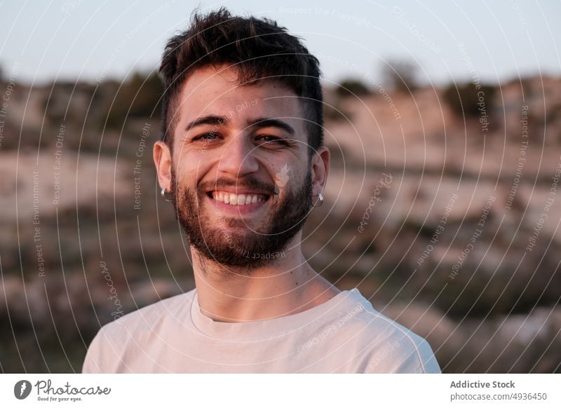 Cheerful young man in countryside smile summer happy weekend portrait holiday earring appearance charismatic male beard positive field cheerful nature glad