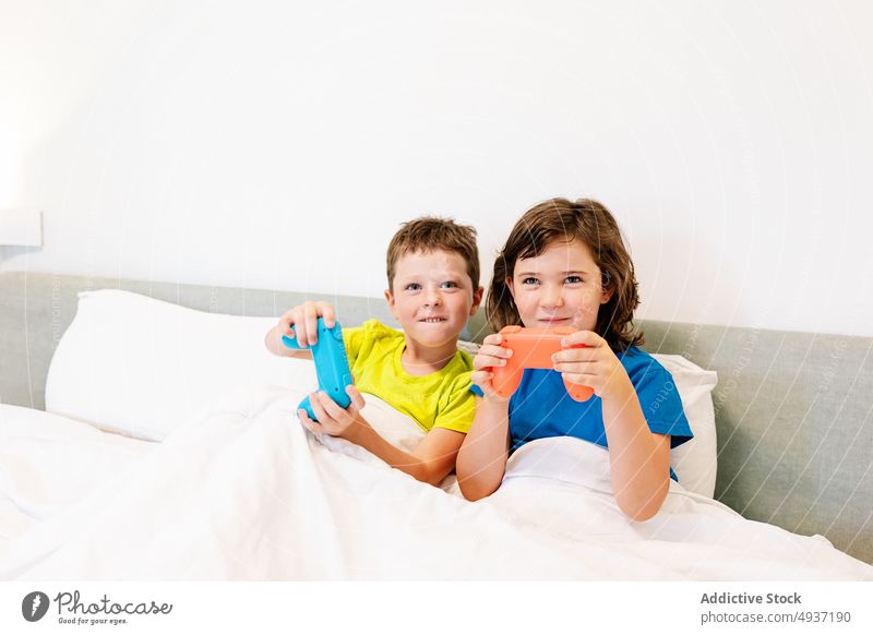 Children playing video game in bed - a Royalty Free Stock Photo