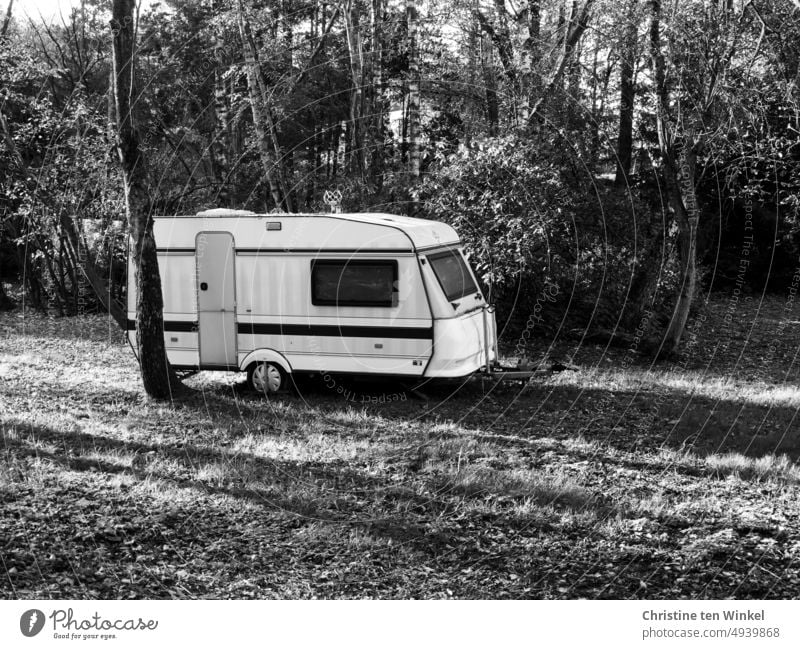 An old caravan in a meadow with trees and shrubs and long shadows Caravan Camping Vacation & Travel Camping site Relaxation Retro Mobility Leisure and hobbies