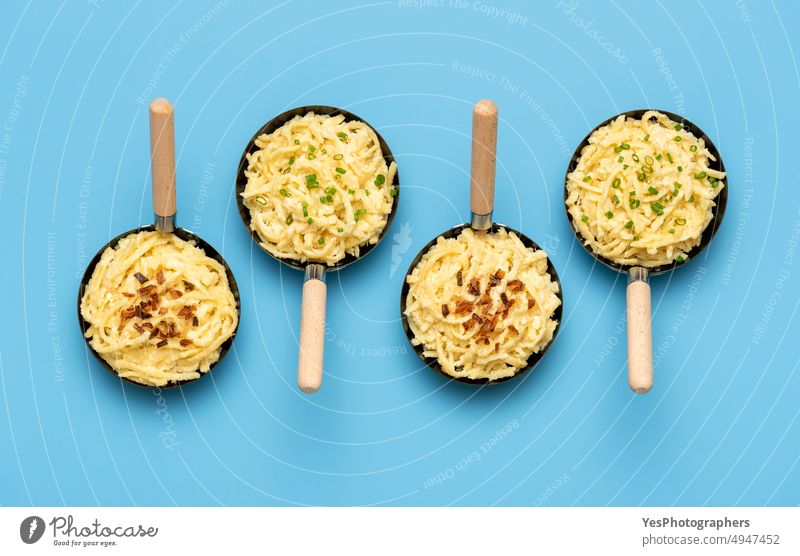 Spaetzle in iron pans on a blue table. German noodles with roasted onion and chives above austrian background baked bavarian carbs cheese color cooked cuisine