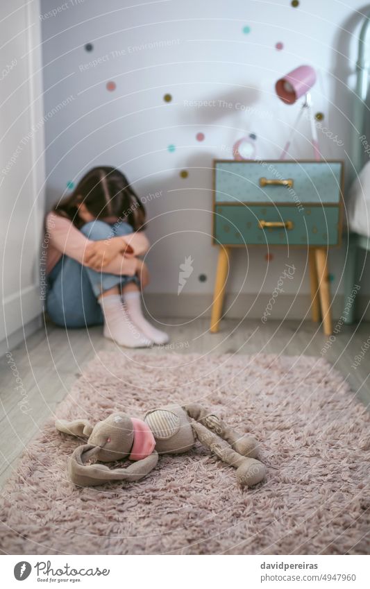 Sad little girl sitting on the floor of her bedroom with stuffed toy lying unrecognizable sad sadness depressed childhood angry mental disorder fear teddy bear