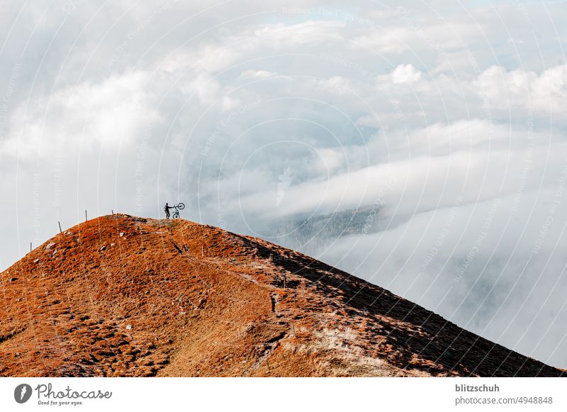 Mountain biker in the Swiss Alps in autumn enjoying the special cloud panorama on the summit Adventure mountains outdoor outdoor sports cycling Sports Autumn