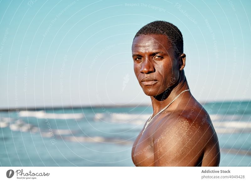 Black male tourist standing near sea man beach summer weekend resort vacation holiday coast shore tourism activity water african american ethnic black sand