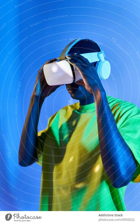 Young African American male watching video in VR goggles man virtual reality concentrate immerse vr experience explore futuristic cyberspace simulate young