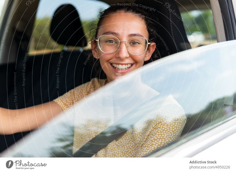 Young smiling woman driving modern car drive road trip steering wheel summer control commute casual female young driver vehicle travel transport daytime
