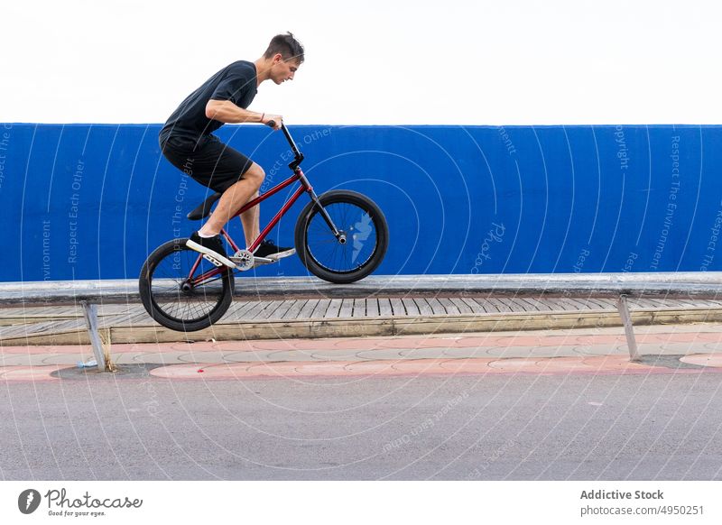 Man doing jump trick on BMX bike man bicycle bmx wall street weekend summer activity male energy urban stunt casual cyclist bicyclist contemporary practice move
