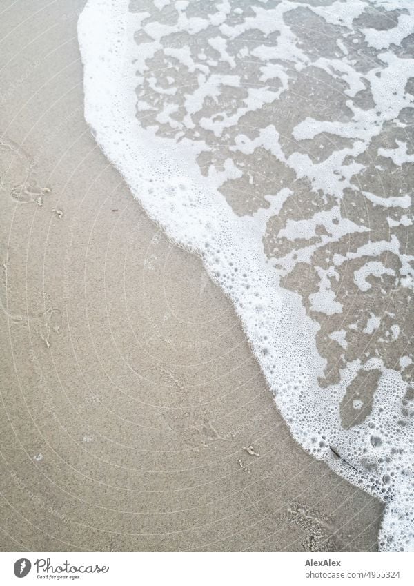 Sandy beach with sea water and spray with footprints Beach Ocean Wet Water White crest Blow Waves coast Vacation & Travel Nature Foam Exterior shot Colour photo