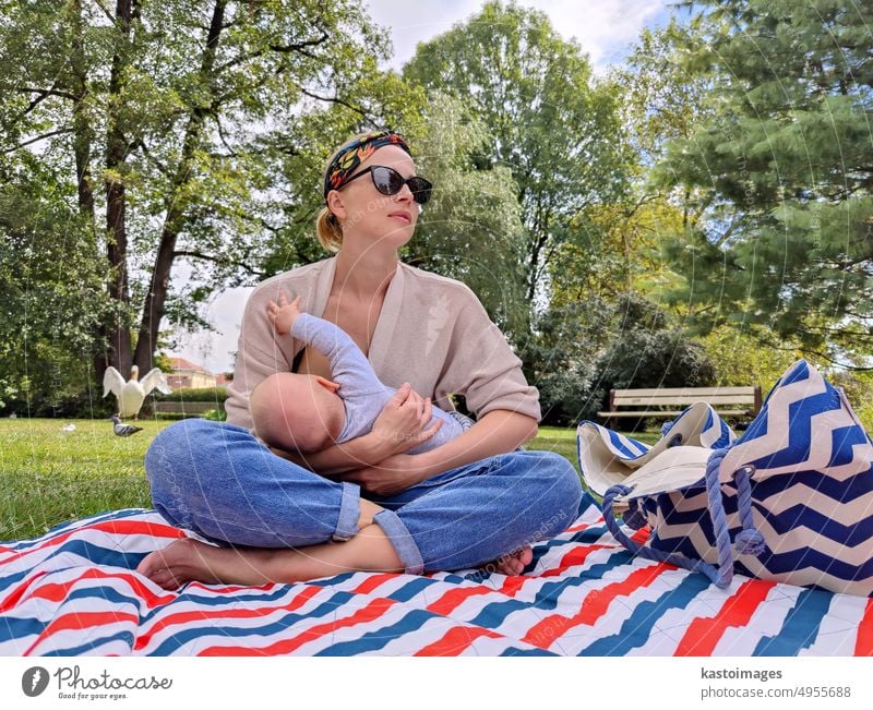 Modern trendy mum breastfeeding his baby boy child outdoors in public city park motherhood childhood woman lifestyle mom family happy care together healthy