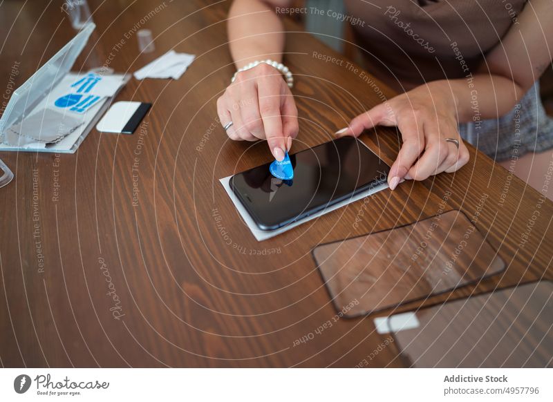 Crop female technician removing dust from smartphone screen woman remove absorber clean sticky table workshop prepare mobile gadget device cellphone digital fix