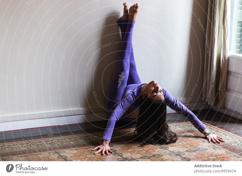 Young slim woman performing Trikonasana yoga pose with support of ethnic  female trainer - a Royalty Free Stock Photo from Photocase