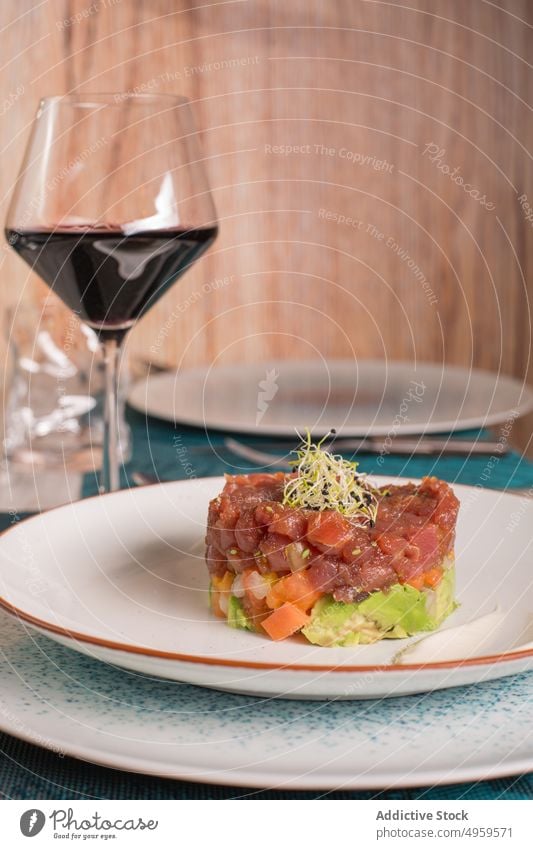 Appetizing tuna tartare on plate in restaurant dish serve delicious food meal cuisine fish seafood glass wine table red wine sauce gourmet palatable exquisite