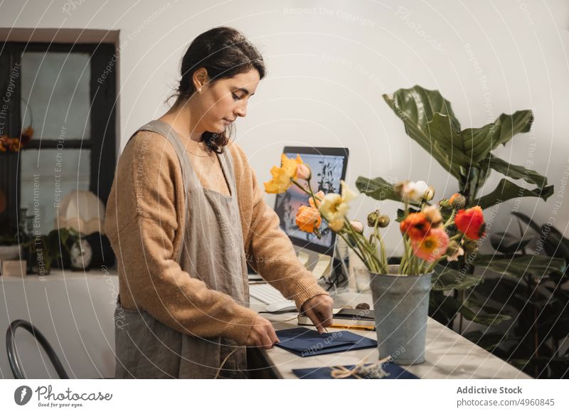 Pensive adult woman making decorative envelopes for selling whil - a  Royalty Free Stock Photo from Photocase