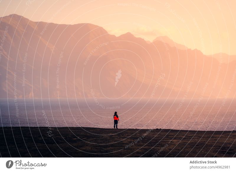 Anonymous traveler standing along seashore in mountains woman sunset coast highland rocky explorer walk gran canaria canary islands stroll nature sky beach