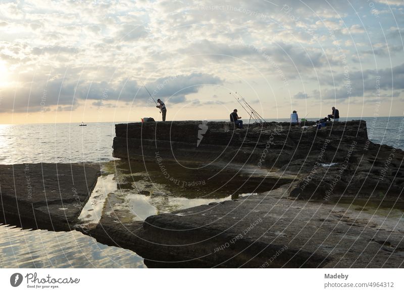 The pink rocks in summer sunshine with anglers on the coast of the Black Sea in Kefken in the province of Kocaeli in Turkey boulders Brocken rock formation