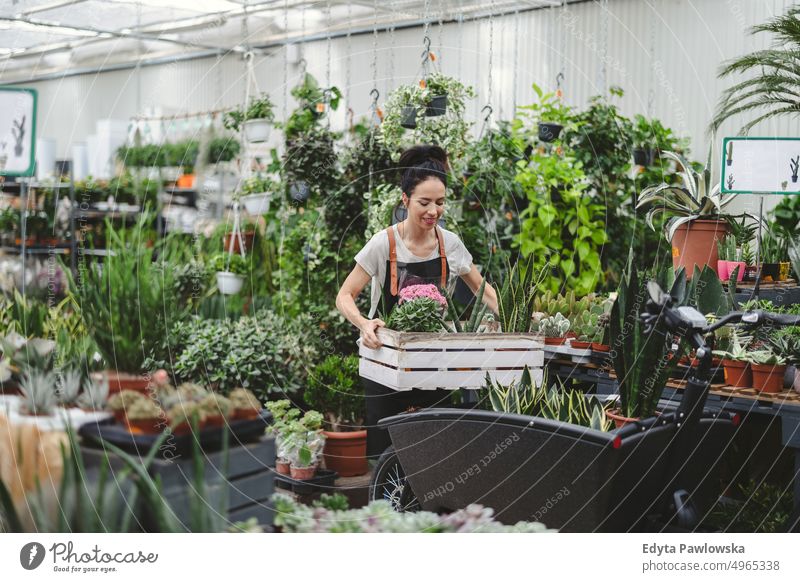 Woman working in a garden center plant nursery smiling positivity nature gardening cultivate growth hobby freshness growing flora green flowers planting pruning
