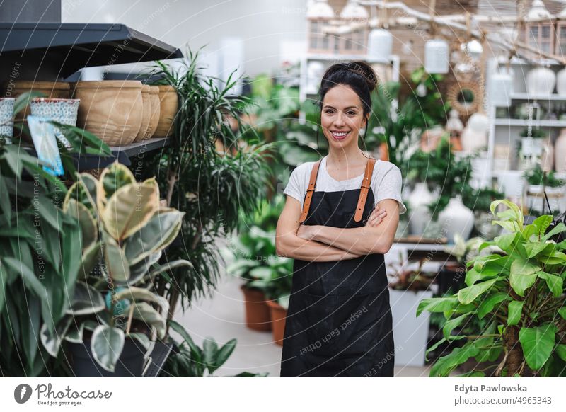 Smiling employee in garden center plant nursery smiling positivity nature gardening cultivate growth hobby freshness growing flora green flowers planting