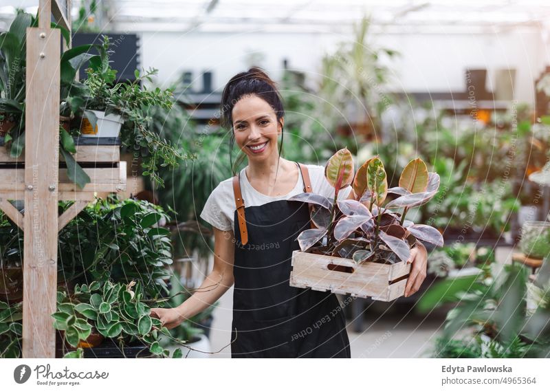 Woman working in a garden center plant nursery smiling positivity nature gardening cultivate growth hobby freshness growing flora green flowers planting pruning