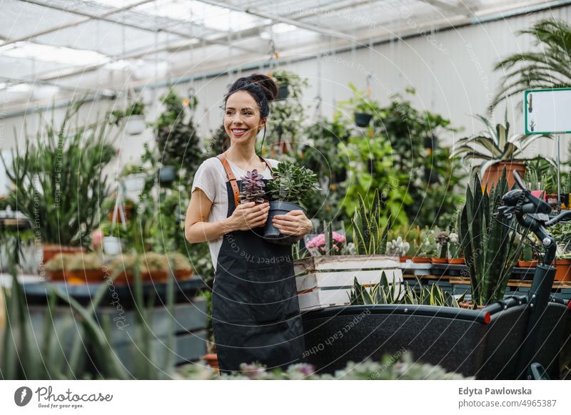 Woman working in a garden center plant nursery smiling positivity nature gardening cultivate growth hobby freshness growing flora green flowers planting pruning