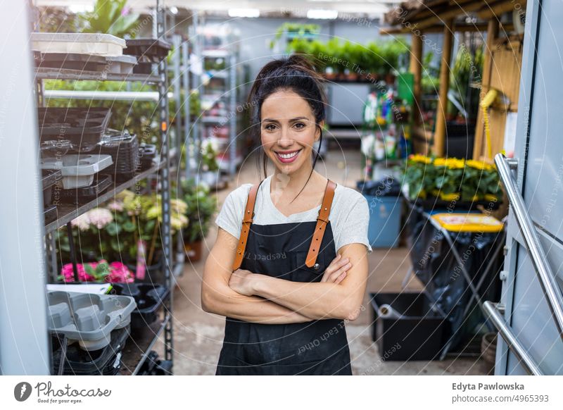 Woman working in a garden center plant nursery smiling positivity nature gardening cultivate growth hobby freshness growing flora green flowers planting pruning