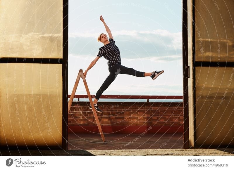 Young choreographer posing on stepladder on roof athlete equilibrium stretching flexible talented graceful empty young man male dancer performer handsome