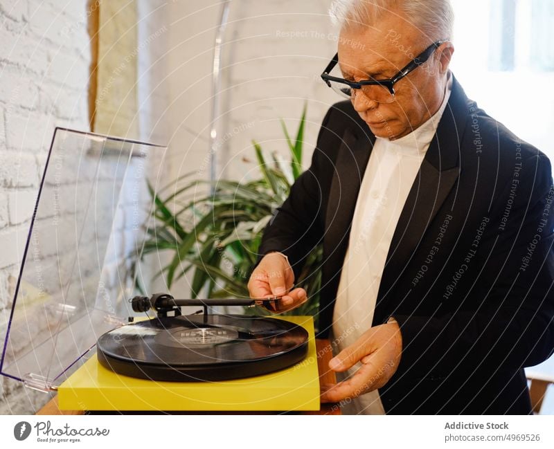 Aged man putting vinyl record into record player music aged disc nostalgia senior listen retro elegant male hobby enjoy tune jacket vintage audio melody sound